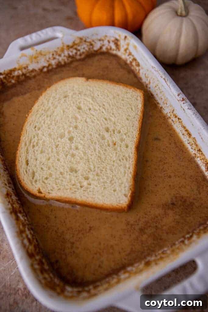 Effortless Pumpkin French Toast Delight 7 A slice of bread being carefully soaked in the rich pumpkin custard, absorbing the flavors.