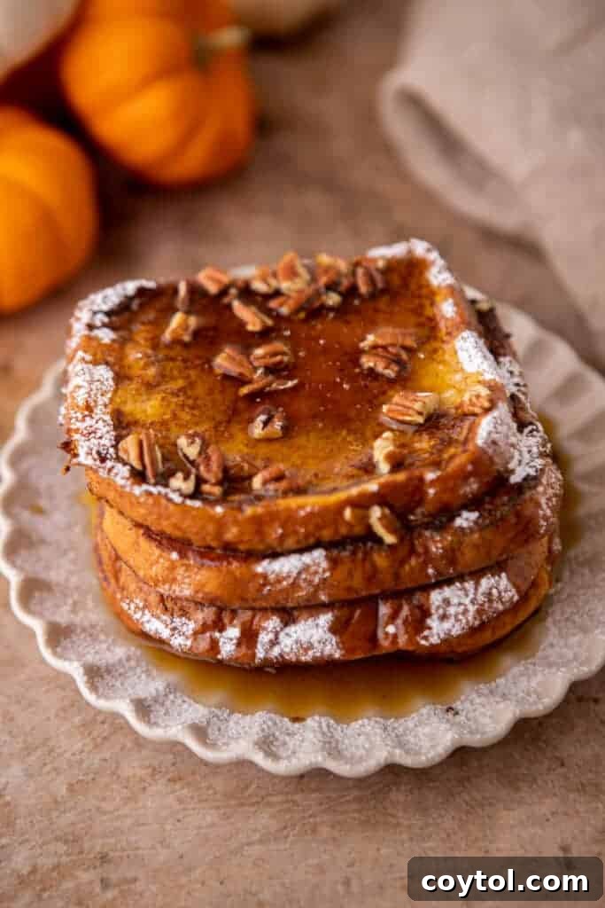 Effortless Pumpkin French Toast Delight 10 Two slices of pumpkin french toast, artfully arranged on a plate with scattered pecans and a rich drizzle of maple syrup, invitingly ready to be enjoyed.