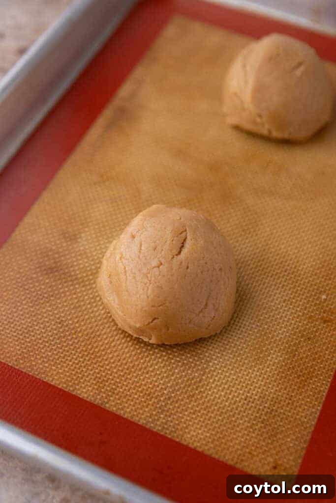 Cookie dough ball stuffed with cookie butter on a baking sheet.