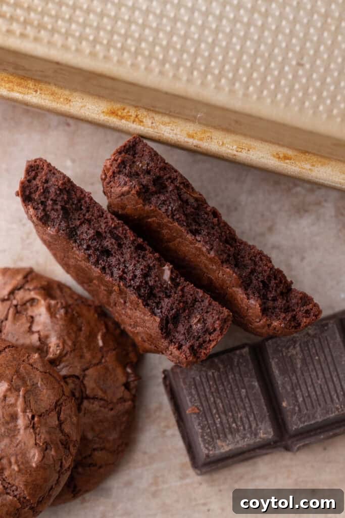 A small batch brownie cookie cut in half, revealing its fudgy, moist interior and delicious, rich texture.