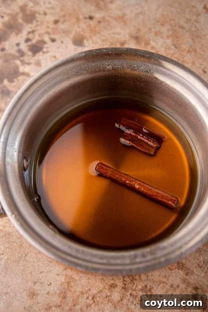 Starbucks Iced Apple Crisp Oatmilk Shaken Espresso 6 Apple crisp syrup simmering in a saucepan on the stovetop, infusing with cinnamon sticks and brown sugar.