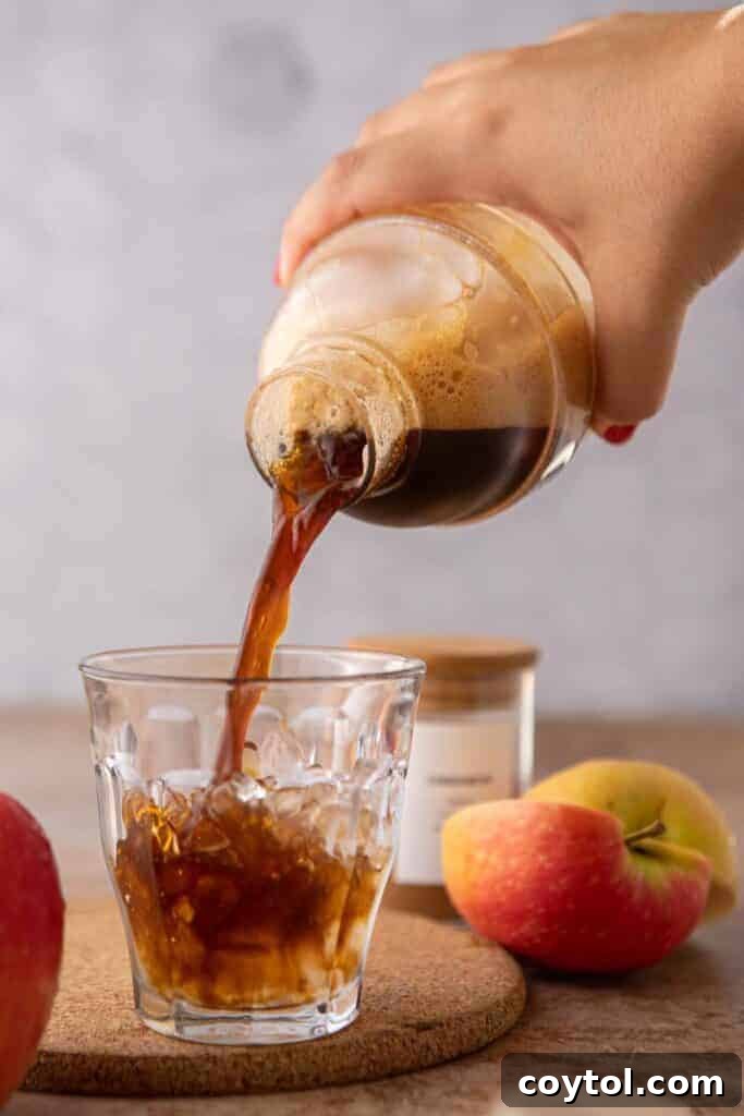 Starbucks Iced Apple Crisp Oatmilk Shaken Espresso 8 The shaken espresso and apple crisp syrup mixture being poured over ice into a tall glass, creating a rich base for the drink.