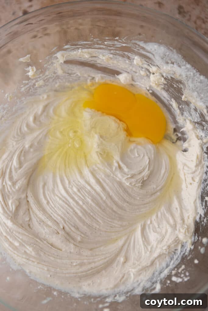 Creamy cheesecake mixture ingredients in a bowl, featuring softened cream cheese, sugar, and vanilla, ready to be blended for a smooth filling.