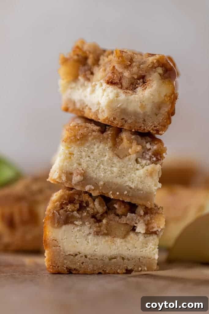 A stack of perfectly sliced apple cheesecake bars with streusel crisp on top, ready to serve.