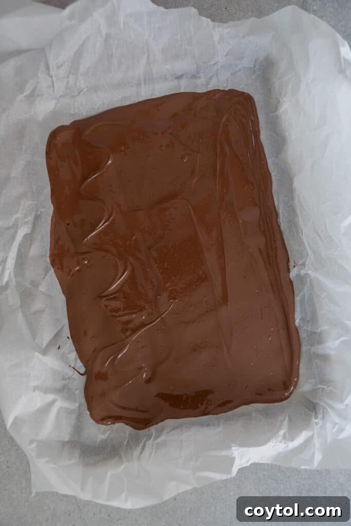 Hauntingly Easy 3-Ingredient Halloween Ghost Bark 5 chocolate spread out on a tray over parchment paper