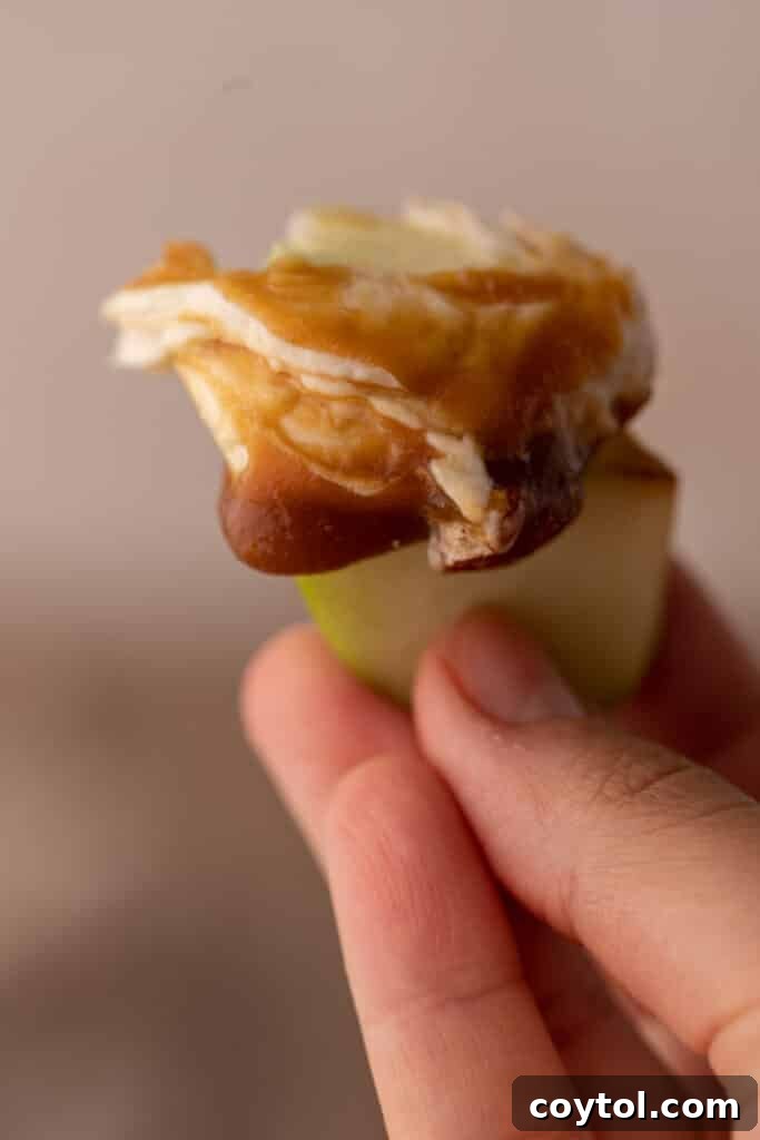 Apple slice being dipped into creamy caramel cheesecake dip