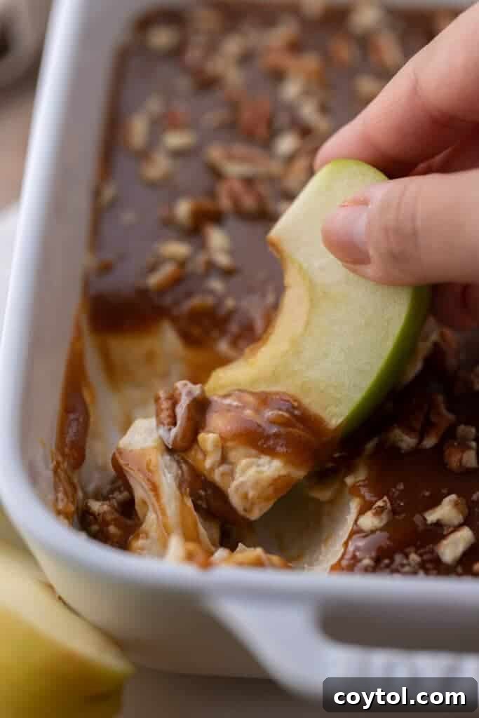 Hand dipping apple in cheesecake dip, a perfect fall snack