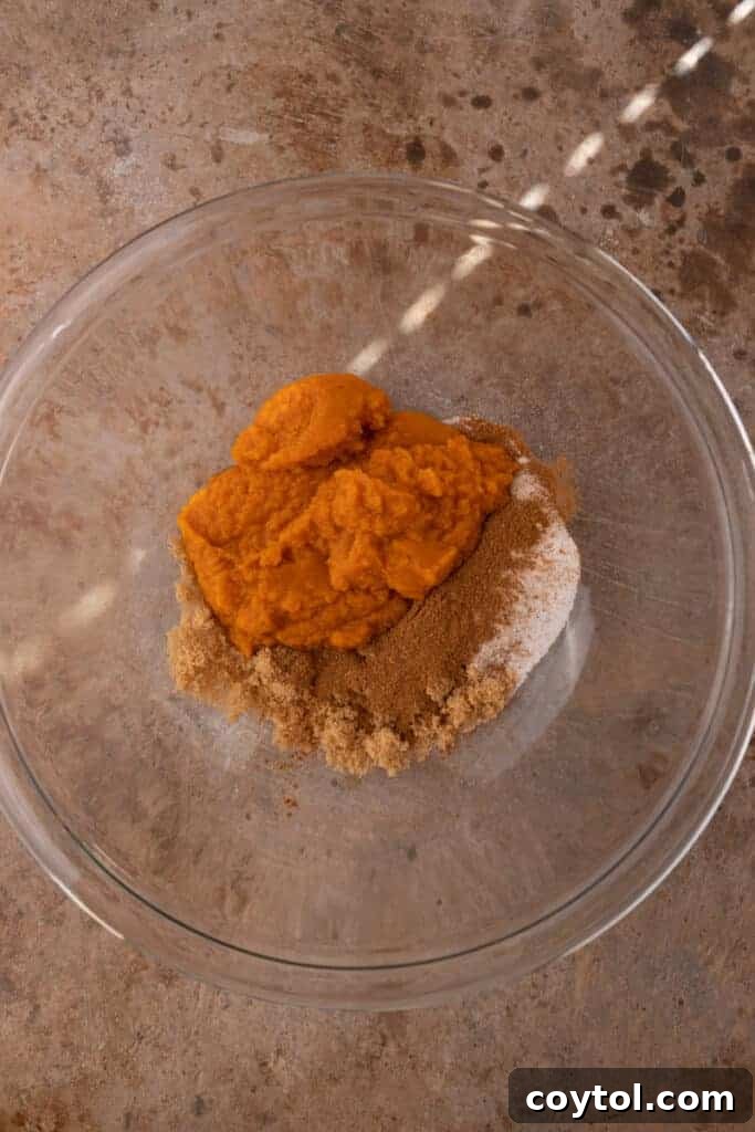 Close-up of ingredients for mini pumpkin pies in a mixing bowl before combining.