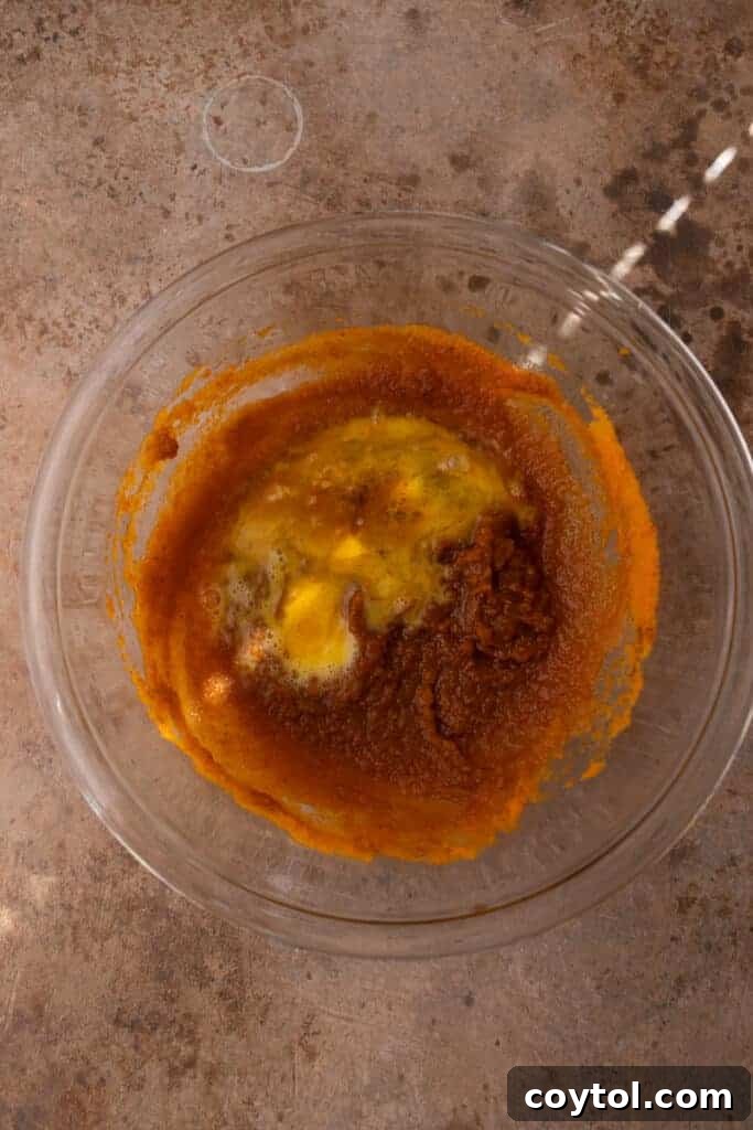 Mixed ingredients for pumpkin pie filling in a bowl, showing a smooth, orange consistency.