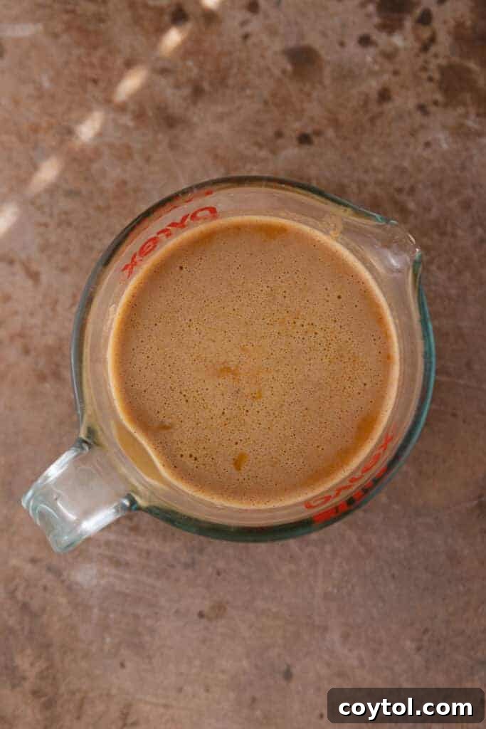 Pumpkin batter poured into a clear measuring cup, showing its smooth texture.