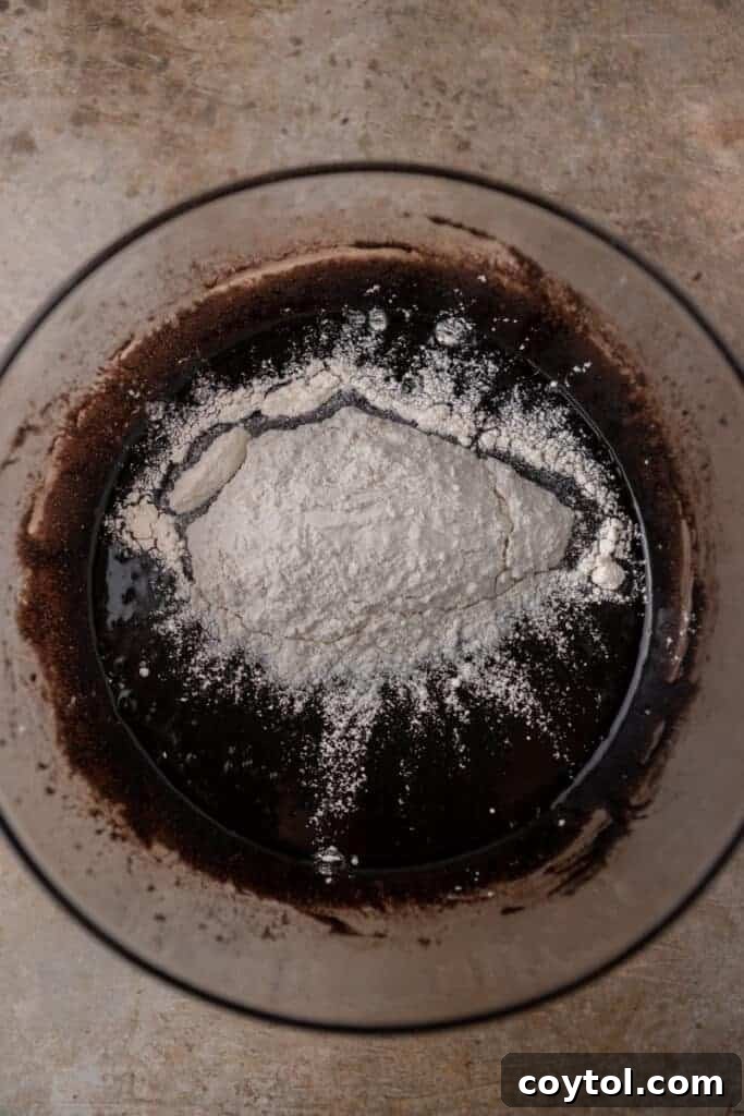 Chocolate batter with flour sprinkled on top, ready to be folded in.