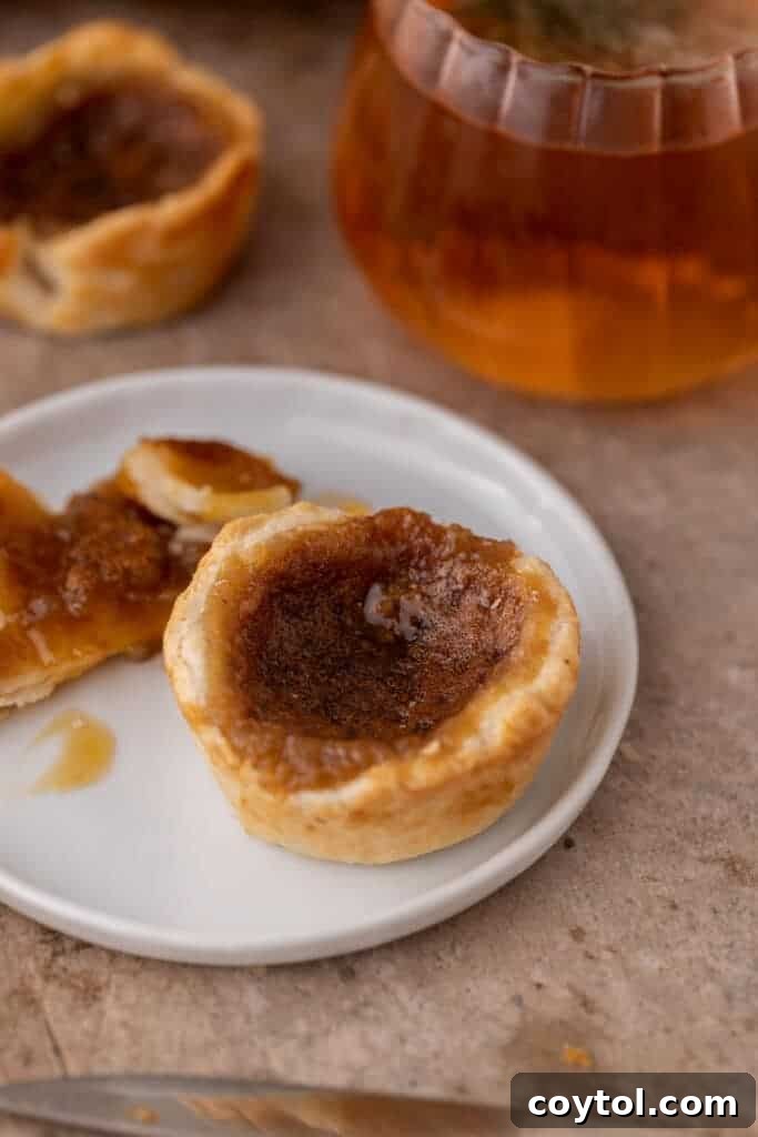 A single mini butter tart presented beautifully on a white plate