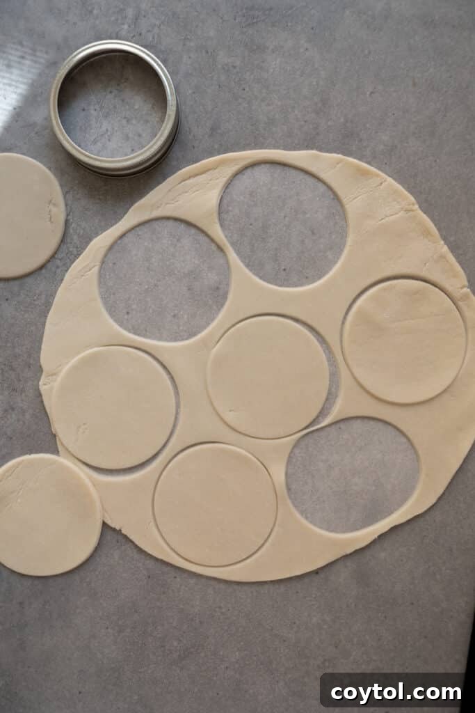Pie crust dough being rolled out on a floured work surface, ready for cutting