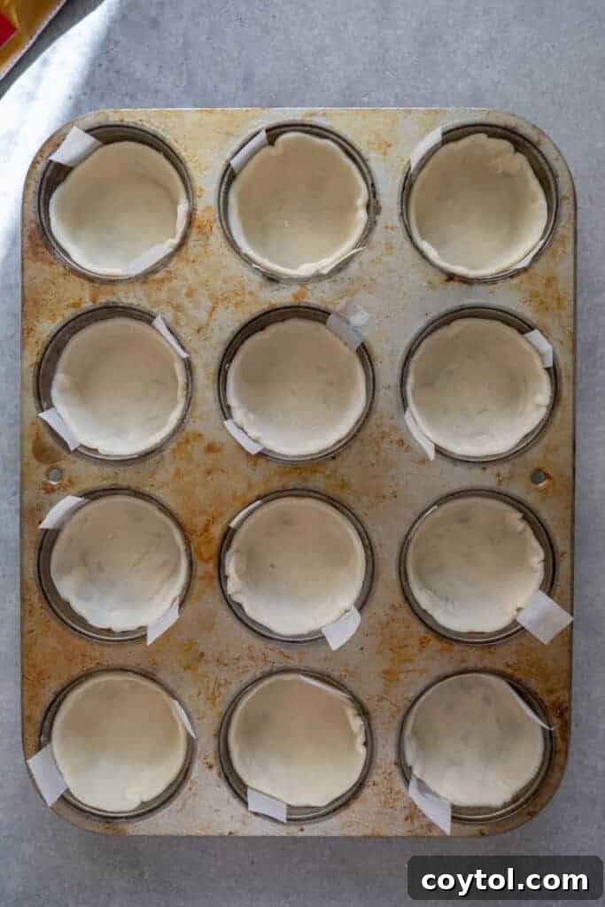 Pie crusts gently pressed into muffin tin cups, forming individual tart shells