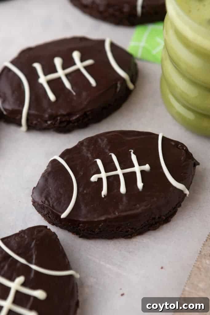 A beautifully arranged plate of football-shaped brownies next to a refreshing drink, perfect for a party.