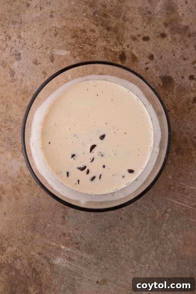 A bowl filled with chocolate chips and hot heavy cream, the beginnings of a rich chocolate ganache.
