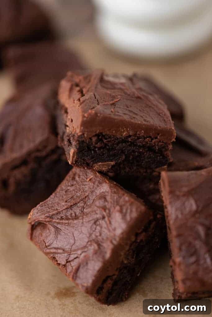 The 4-Minute Frosting Hack for Brownies 3 Stacked brownies generously coated with a thick layer of chocolate frosting, ready to be enjoyed.