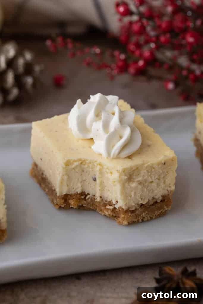 A single eggnog cheesecake bar with a bite taken out, showcasing its creamy texture and graham cracker crust.