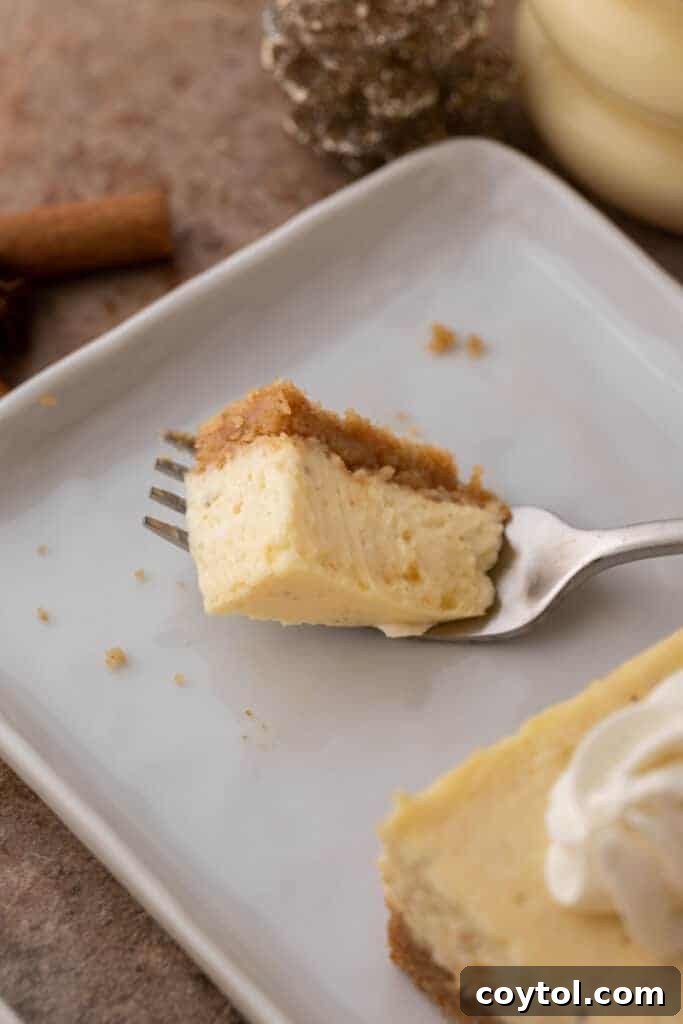 A piece of eggnog cheesecake bar balanced on a fork, showing its soft interior.