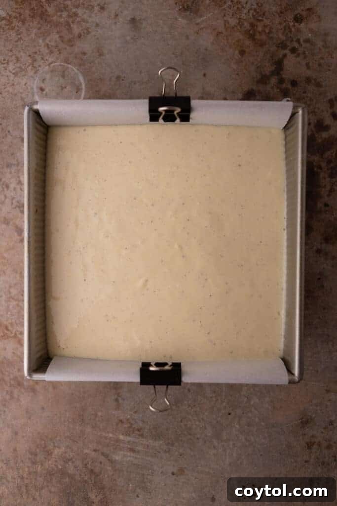 Smooth eggnog cheesecake batter poured into a baking pan over the graham cracker crust, ready for the oven.
