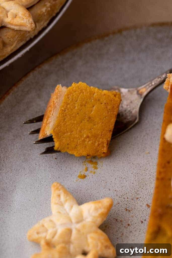 A close-up shot of a fork taking a bite out of a pumpkin pie slice
