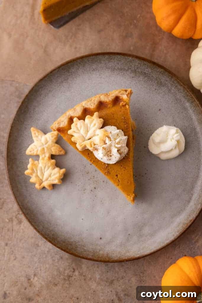 A slice of pumpkin pie on a plate, elegantly served with a dollop of whipped cream on the side