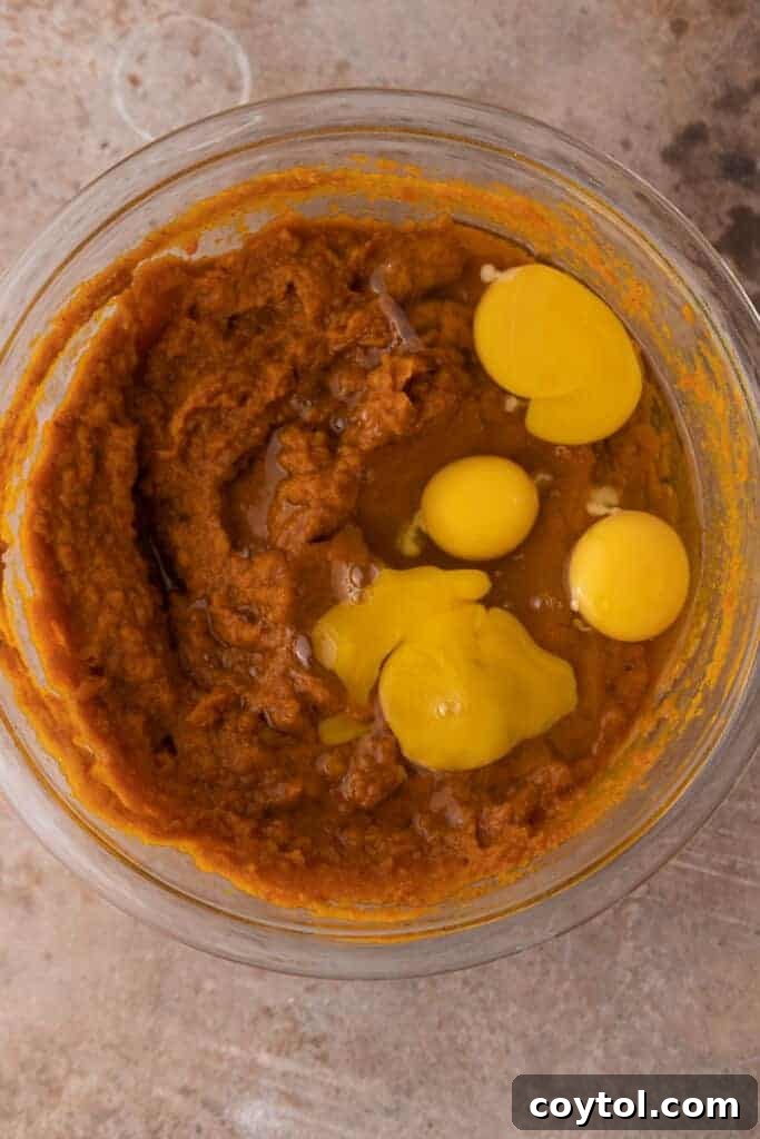 Eggs and pumpkin puree being combined in a bowl for the pie filling