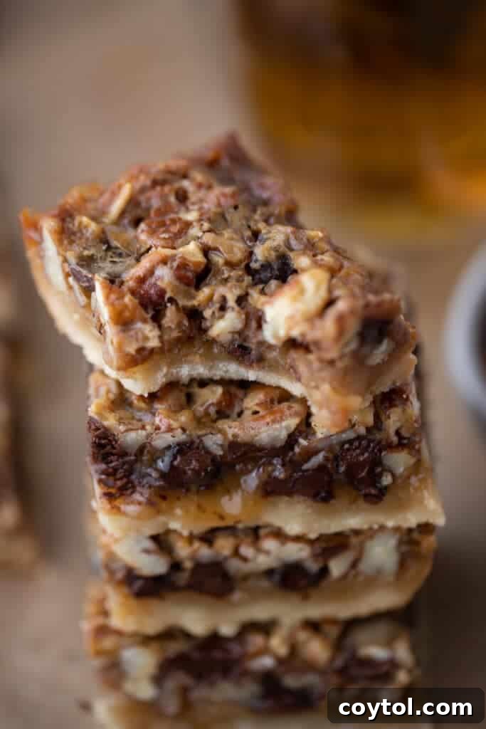 stacked chocolate pecan pie bars, top one has a bite taken out, showing the gooey filling