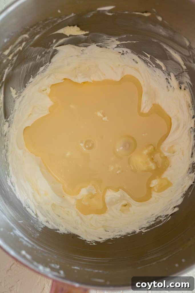 Adding cold sweetened condensed milk to the whipped butter.