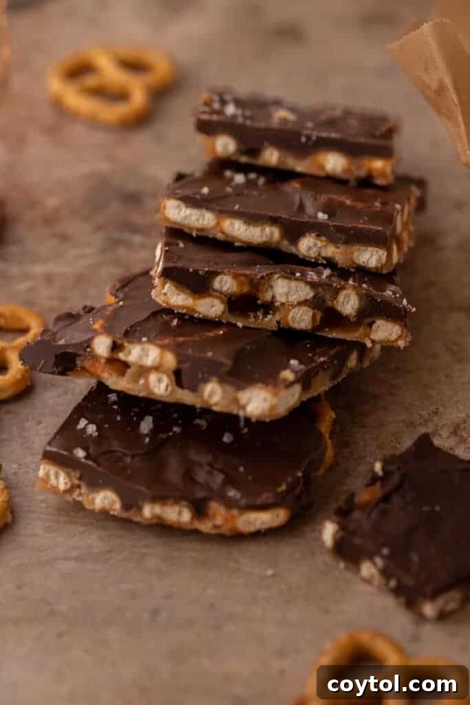Close-up stack of chocolate caramel pretzel bark pieces sprinkled with sea salt. Irresistible holiday dessert.