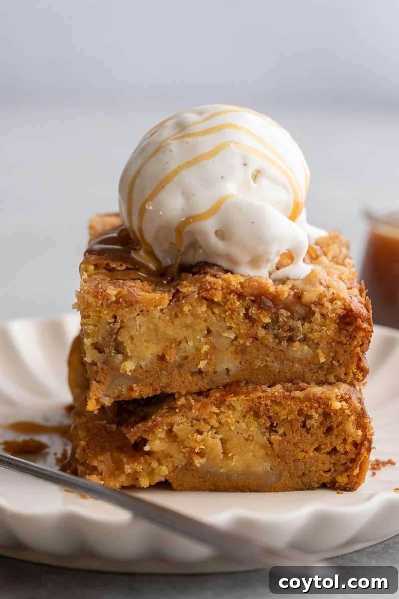 A delicious stack of pumpkin dump cake slices, topped with a scoop of melting vanilla ice cream.