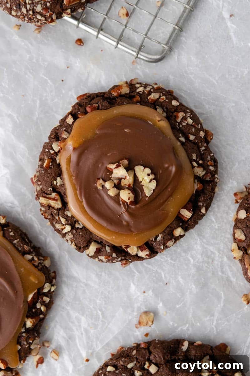 Close-up of Crumbl turtle cookies, drizzled with caramel and chocolate, and topped with pecans.