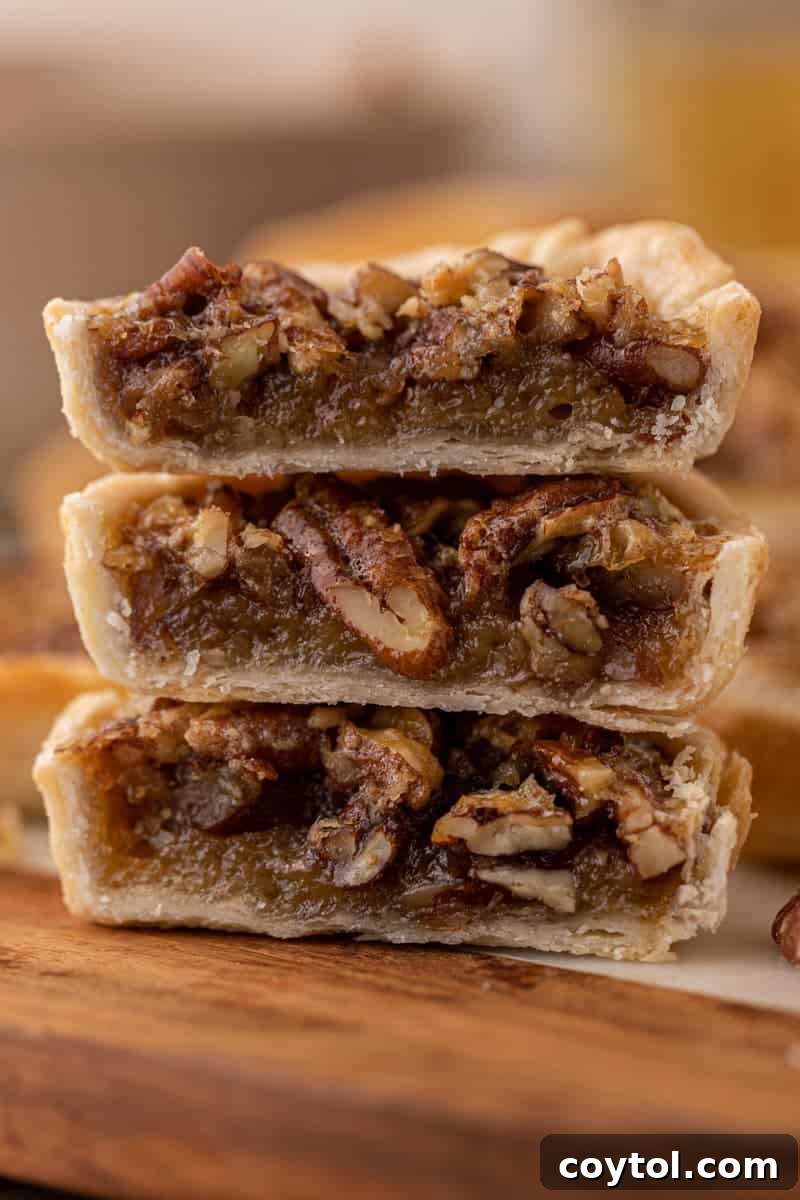 Close-up of a mini pecan pie, cut in half to reveal its rich, gooey filling and golden crust.