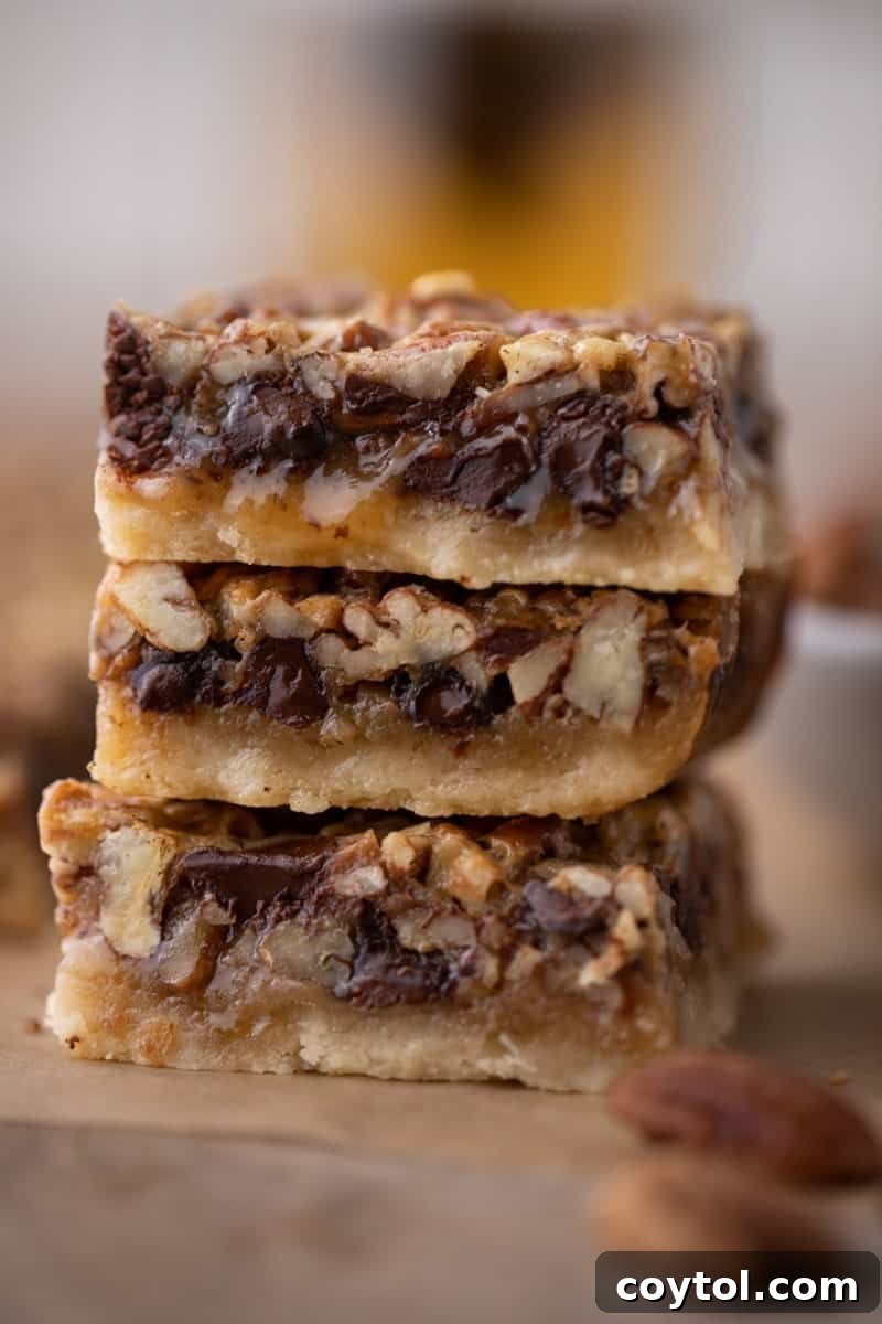 A stack of three rich chocolate pecan pie bars, showing their fudgy texture and pecan-studded tops.