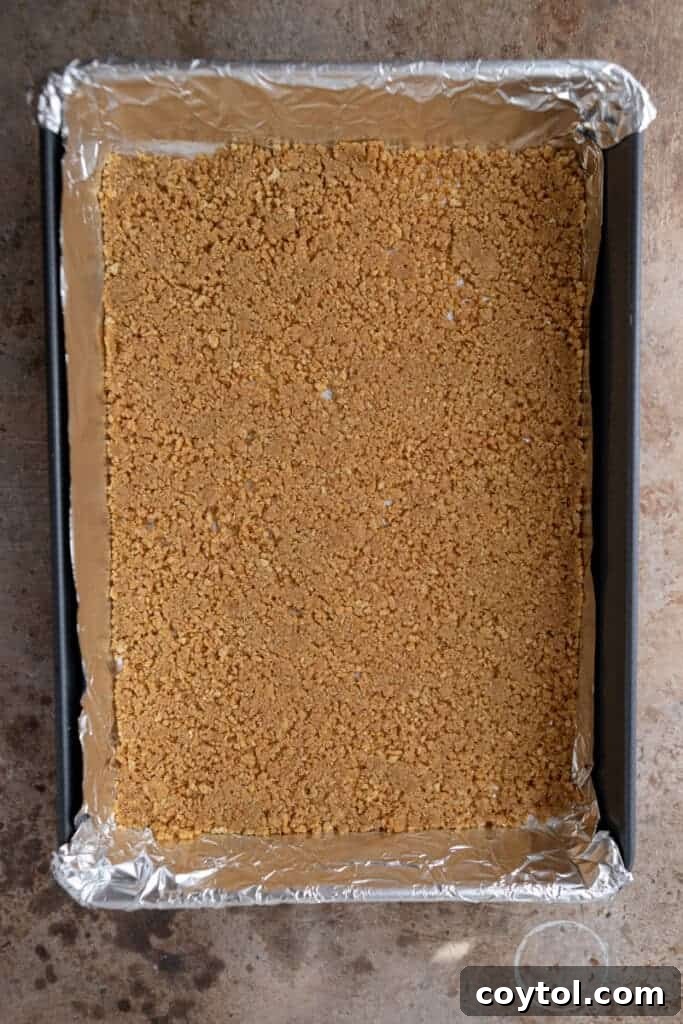 Pressed graham cracker crust in a baking pan, ready for layers
