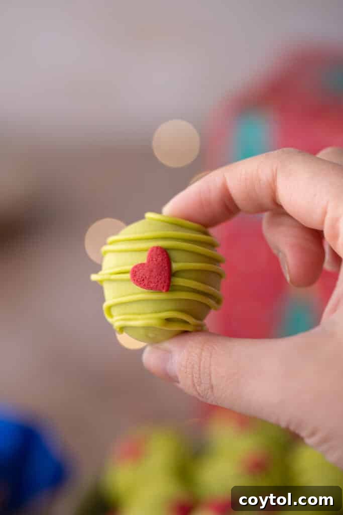 a single oreo ball being held in the air by a hand, ready to be eaten