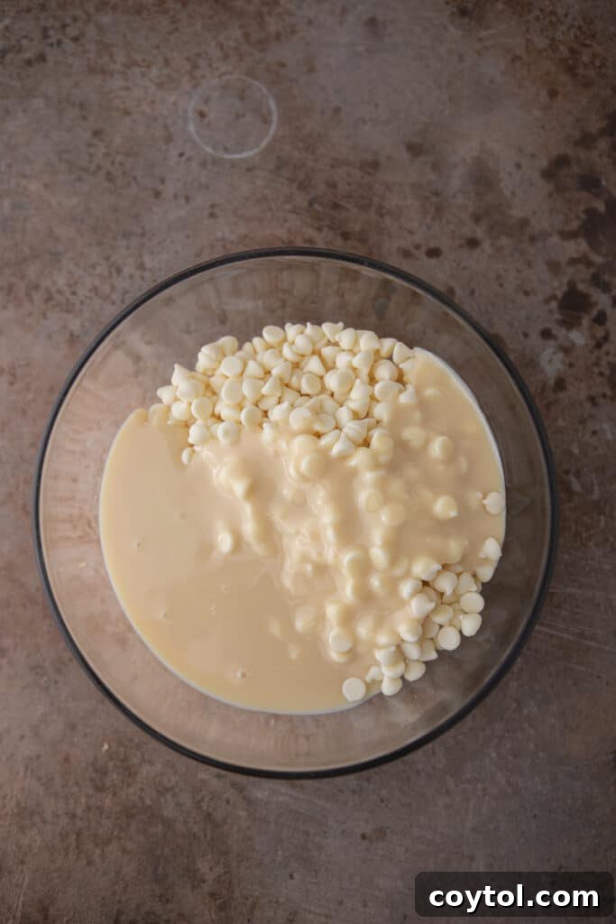White chocolate chips gently melting in a microwave-safe bowl, forming the creamy base of the fudge.