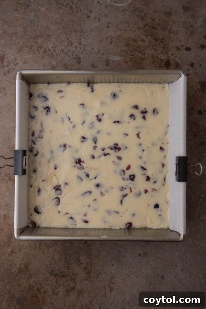 The finished fudge mixture, spread evenly in a parchment-lined square pan, ready for chilling.