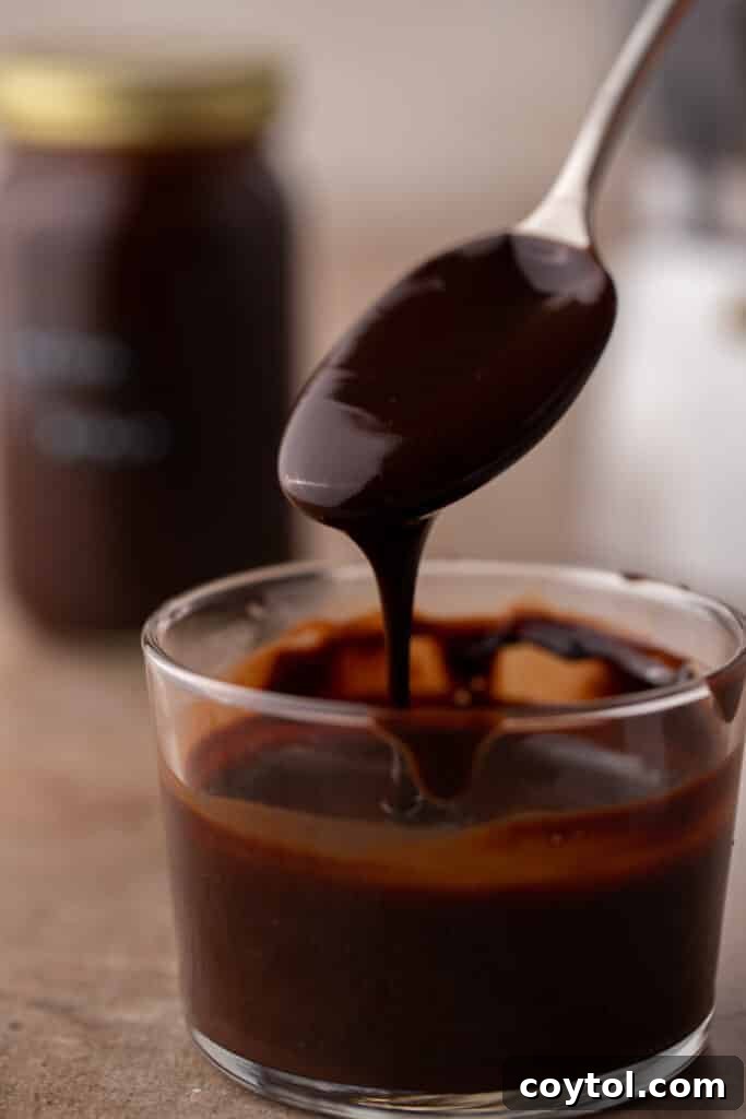 Whip Up Perfect Homemade Mocha Syrup 2 A spoon pouring rich homemade mocha coffee syrup into a cup, showcasing its luxurious texture and color.