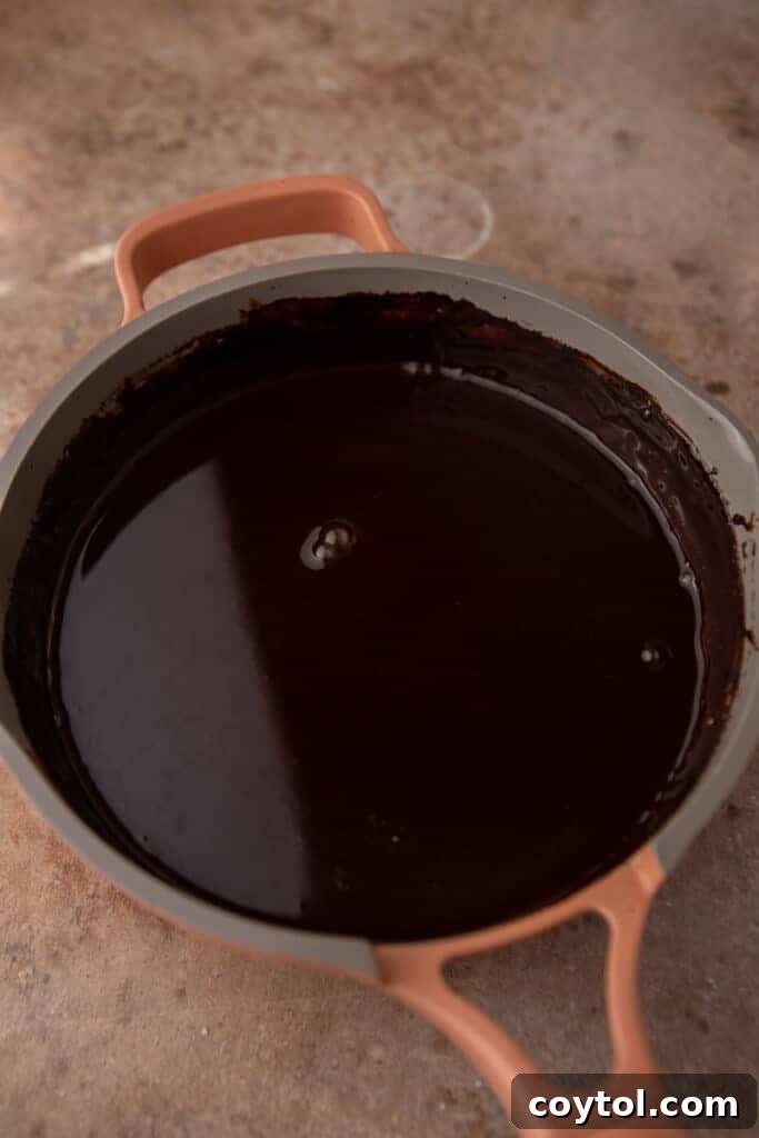Whip Up Perfect Homemade Mocha Syrup 6 Mocha coffee syrup simmering gently in a saucepan, showcasing its darkening color and smooth texture.