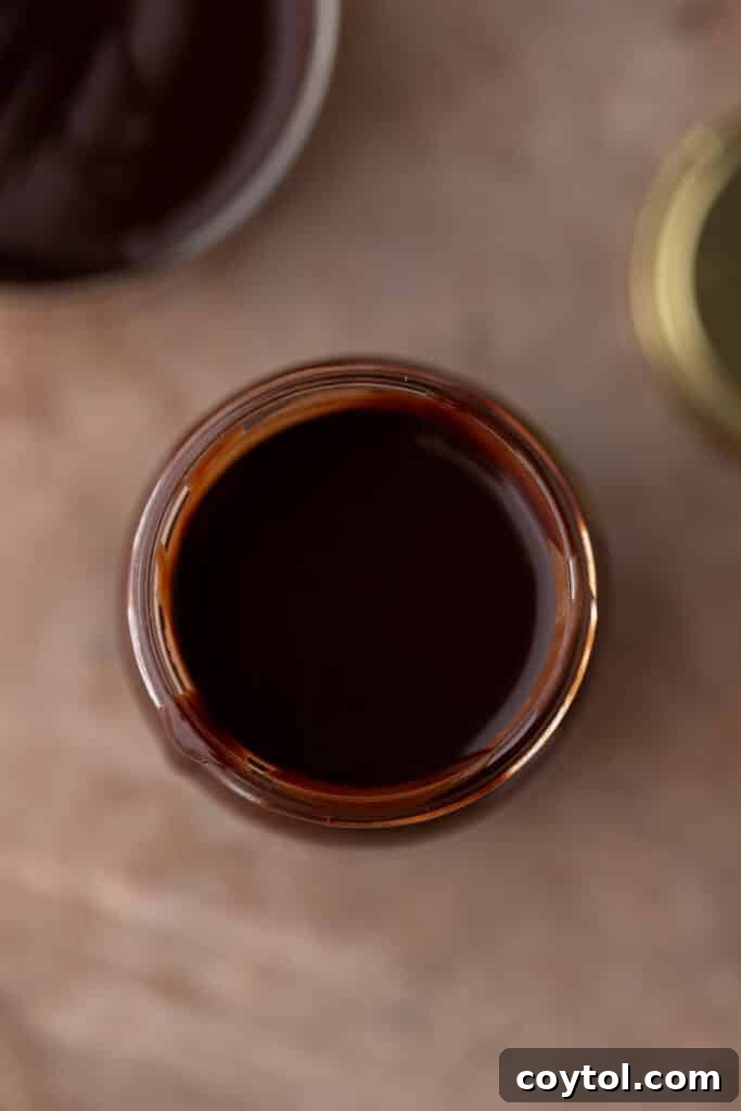Whip Up Perfect Homemade Mocha Syrup 8 Overhead shot of a jar of homemade mocha coffee syrup with coffee beans scattered around, emphasizing its quality.