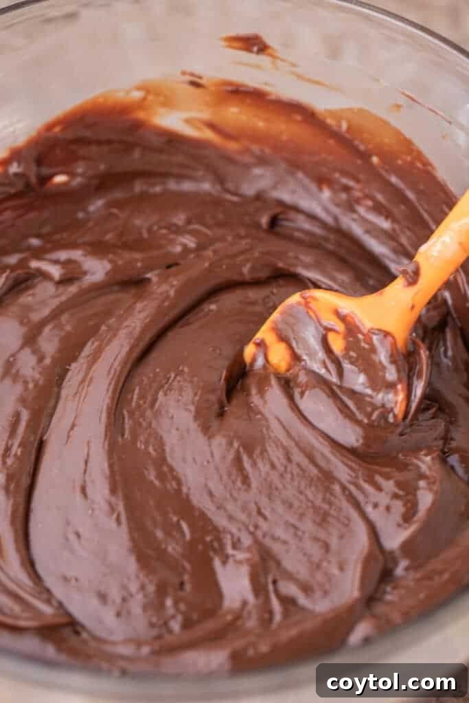 Peppermint fudge recipe ingredients being mixed together in a bowl, showcasing the melting process.