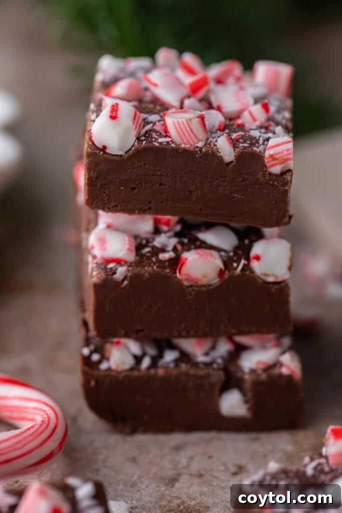 A stack of three neatly cut chocolate peppermint fudge squares, showcasing their perfect texture.