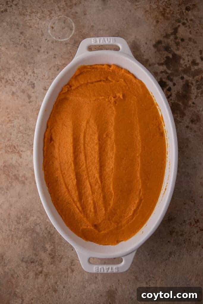 A pan filled with the smooth sweet potato casserole base, awaiting its pecan streusel topping.