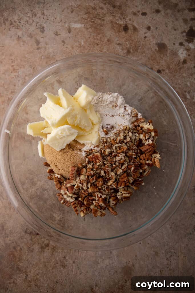 A bowl containing unmixed dry ingredients for the pecan streusel topping, including flour, brown sugar, and chopped pecans.