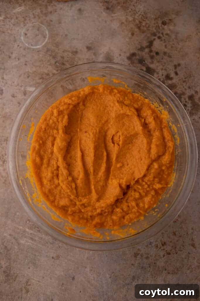 A bowl of creamy, mixed sweet potato base, sweetened and spiced, ready to be transferred to the baking dish.