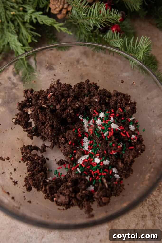 Crumbled chocolate Christmas tree cakes in a bowl with red, green, and white sprinkles mixed in.
