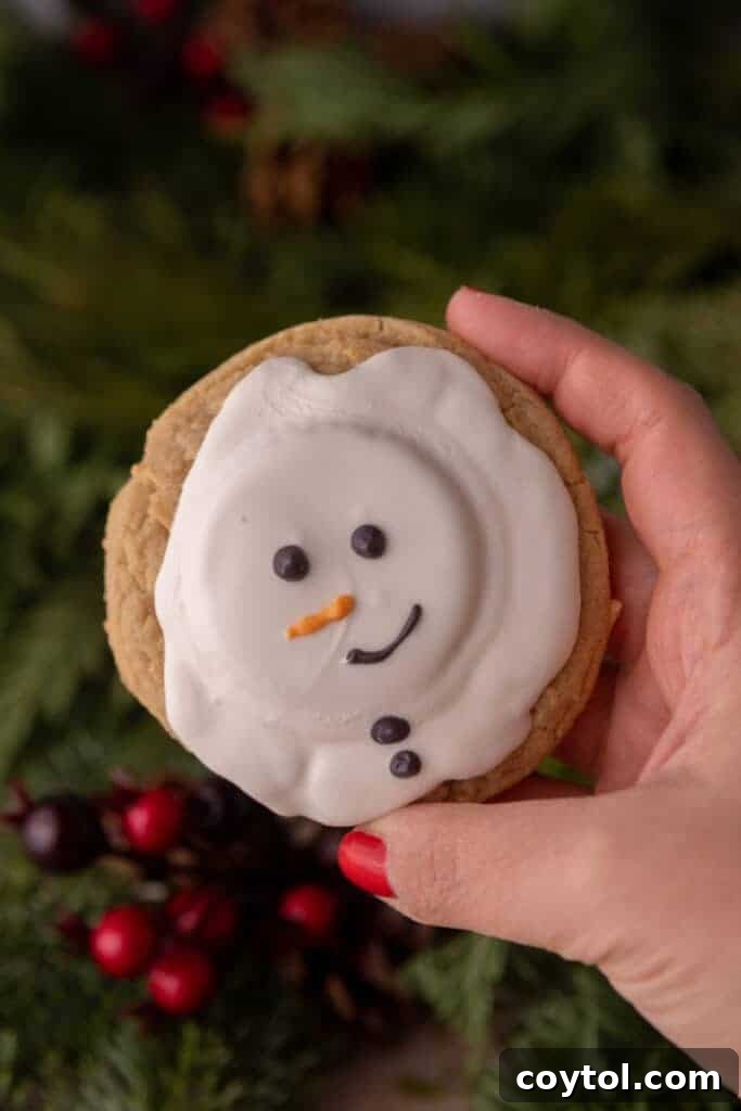 a hand holding up a single melted snowman peanut butter cookie