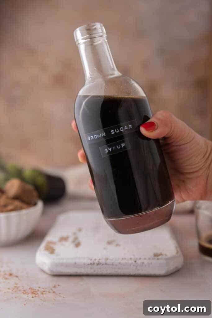A hand picking up a jar of freshly made Starbucks brown sugar syrup, highlighting its homemade appeal.