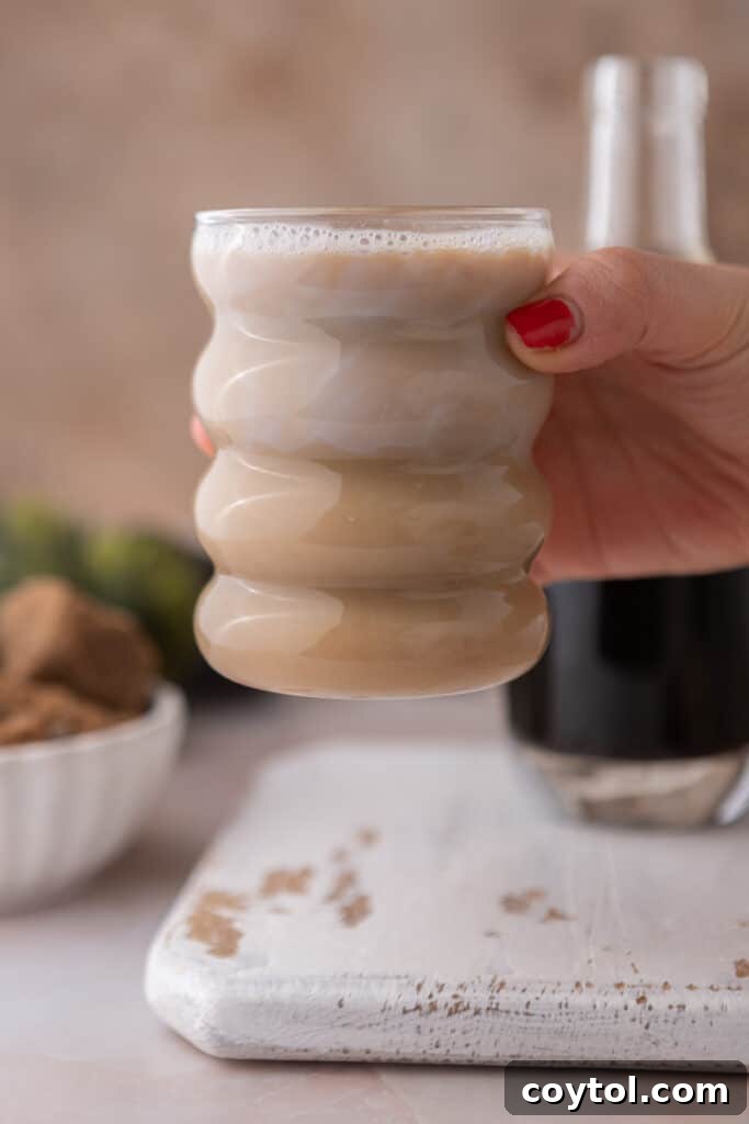 A hand holding up a cup of coffee, showcasing the deliciousness enhanced by brown sugar syrup.